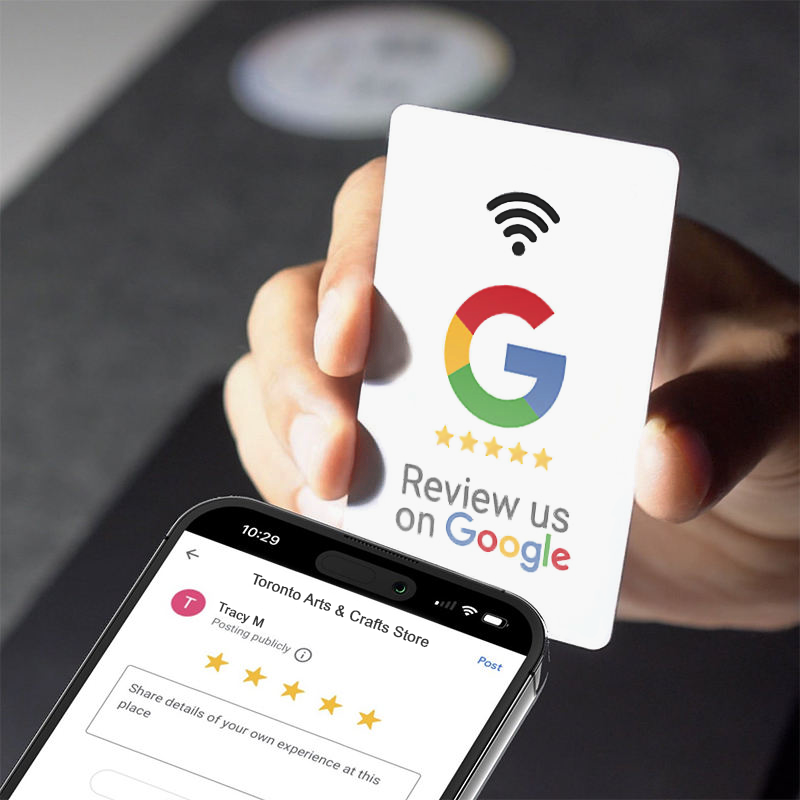 A hand holding a white Vouch NFC review card up to a smartphone, which shows a Google review screen open with a five-star rating already selected.